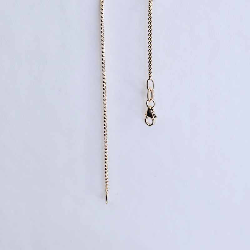 A close-up of a gold-toned chain necklace with a lobster clasp, shown against a plain light gray background.