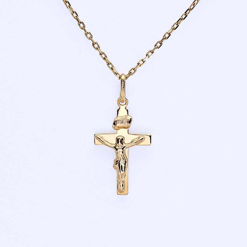 A gold crucifix pendant necklace featuring a detailed figure of Jesus on a rectangular cross, suspended from a delicate gold chain against a light blue background.