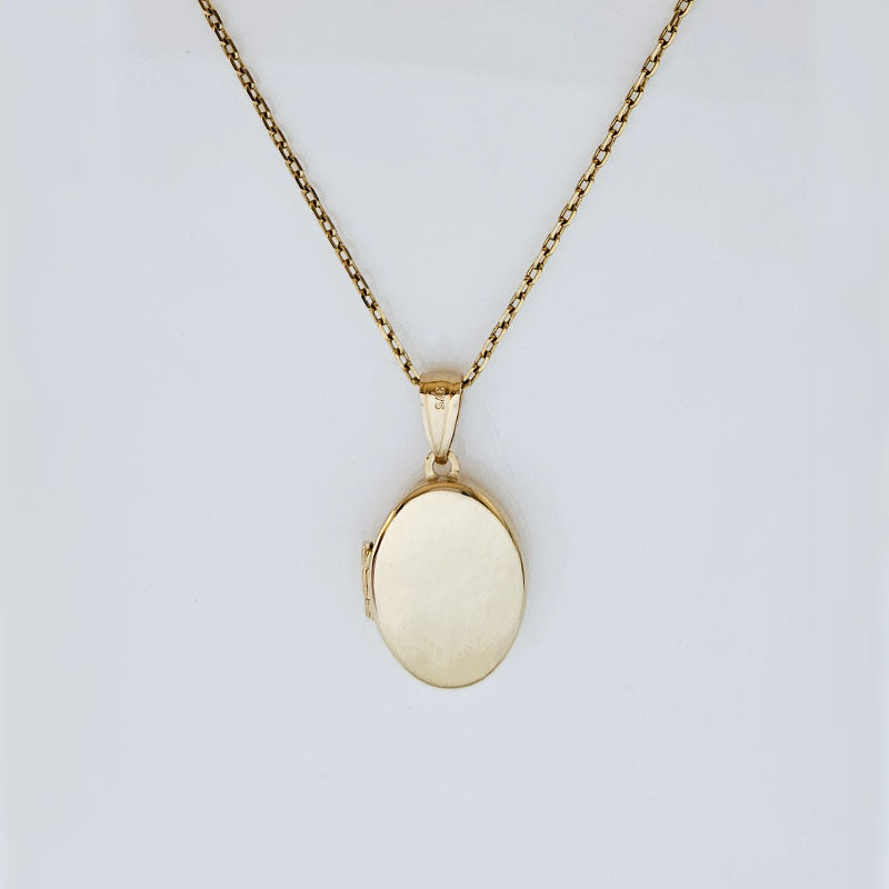 Gold locket necklace on a light gray background
