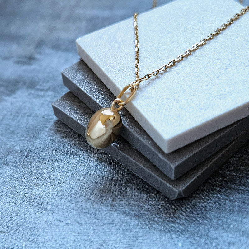 Gold necklace with a pendant on a textured surface