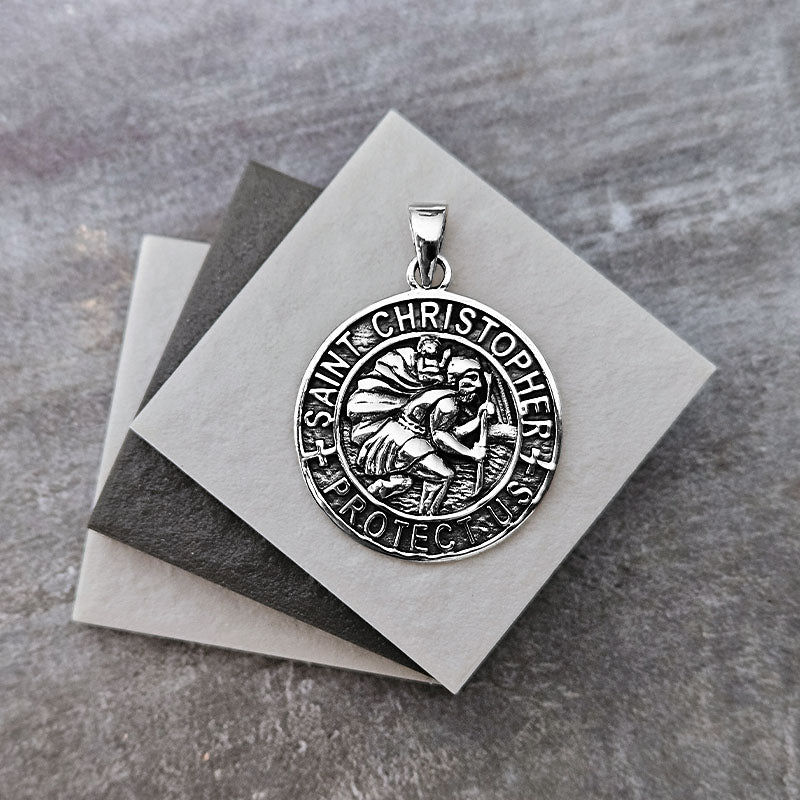 Silver Saint Christopher pendant on gray paper