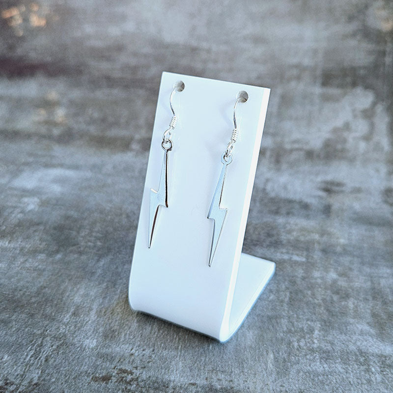 Silver lightning bolt earrings on a white card against a gray background