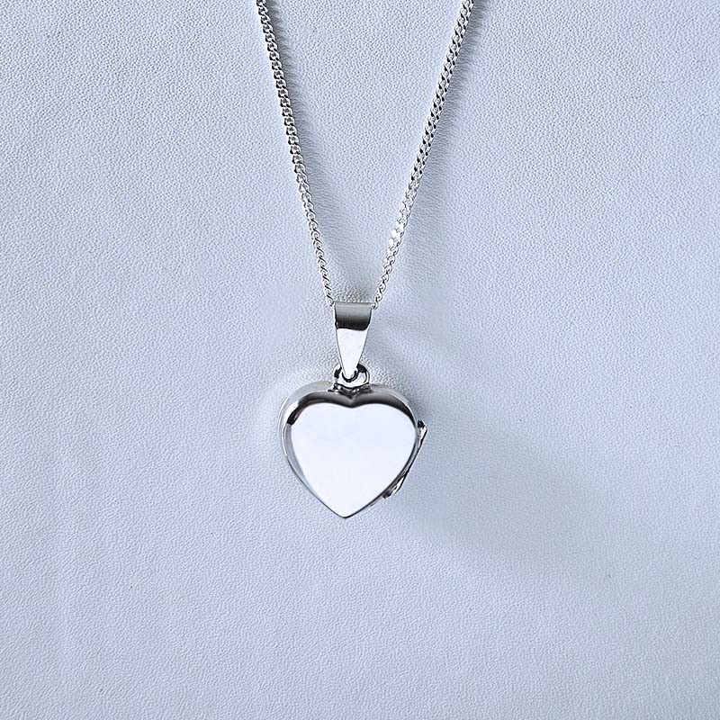 Silver heart-shaped pendant necklace on a light gray background