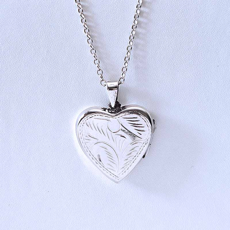 Silver heart-shaped locket on a chain against a light blue background