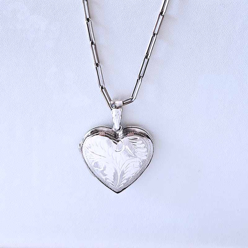 Silver heart-shaped locket on a chain against a light blue background