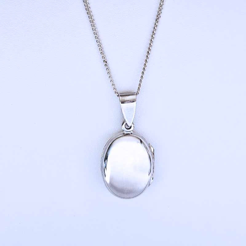 Silver locket on a chain against a light purple background
