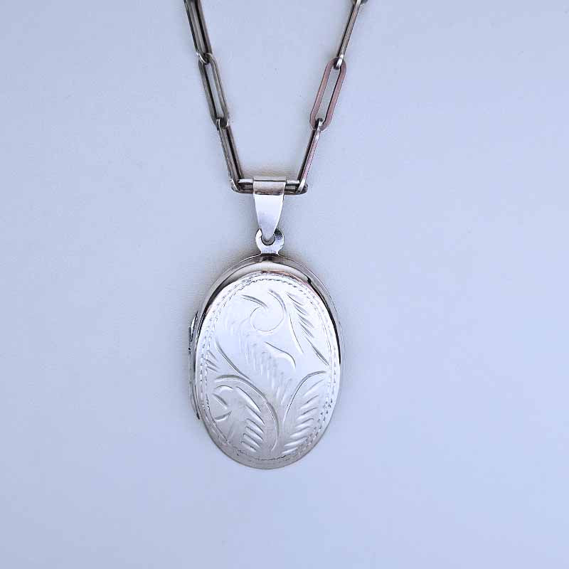 Silver locket with chain on a light gray background