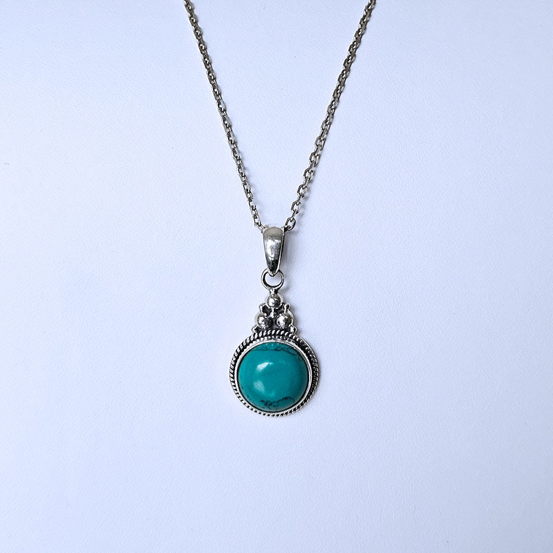 Turquoise pendant necklace on a light blue background