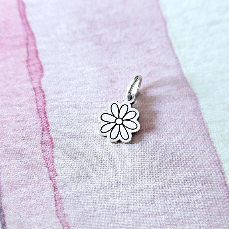 Silver flower-shaped pendant on a pink fabric background