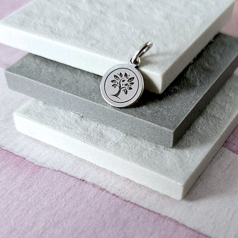Silver pendant with tree design on a stone surface