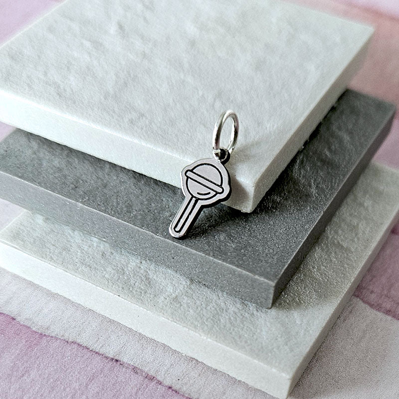 Silver charm shaped like a popsicle on a textured surface