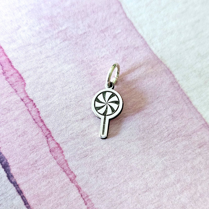 Silver charm on a pink fabric background