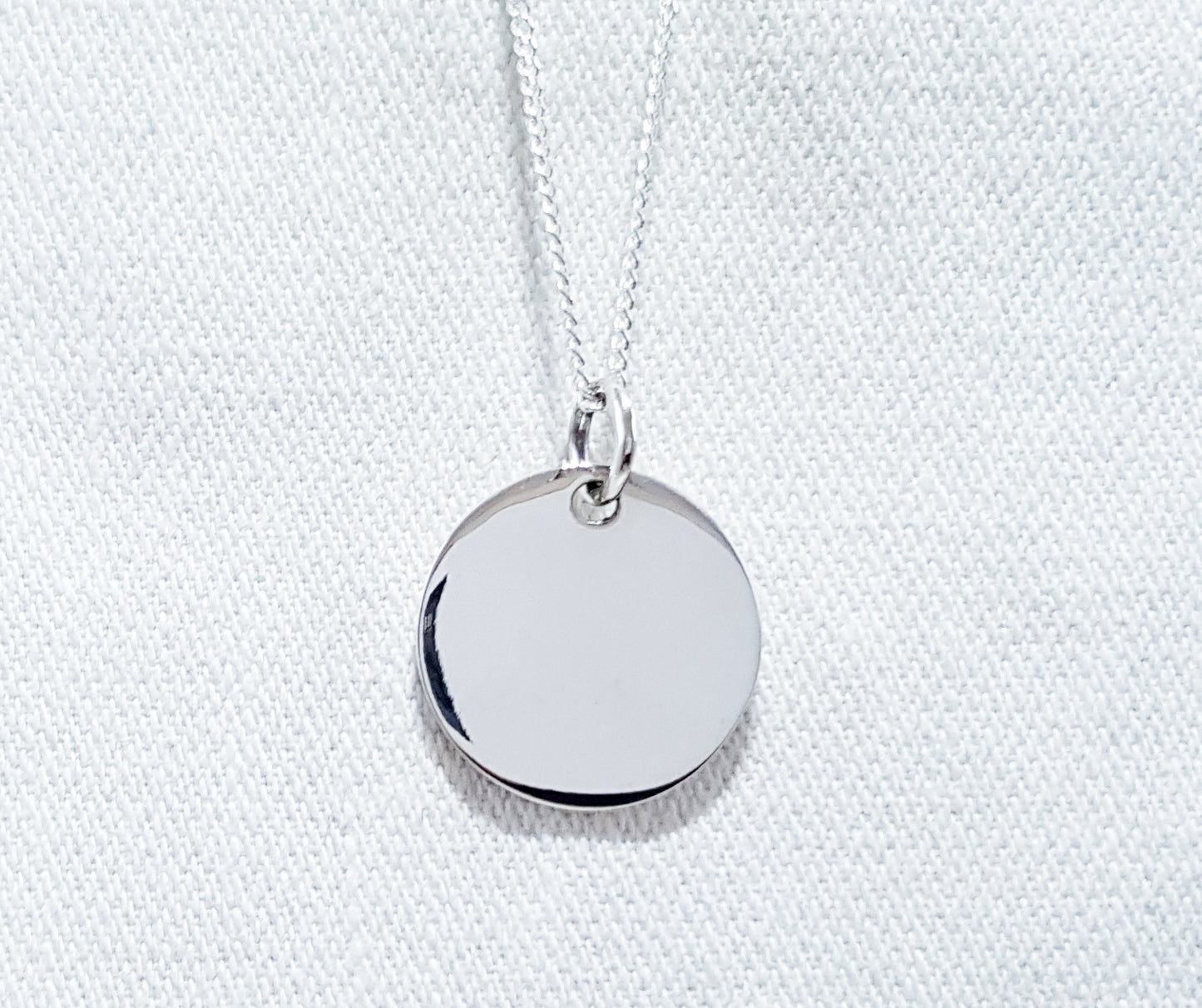 A medium-sized round disc pendant, simple yet stylish in design. The pendant features a smooth and polished circular shape, creating a clean and contemporary look.