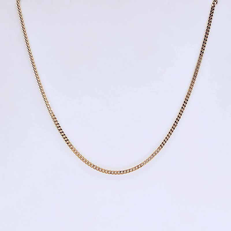 A gold-toned chain necklace with a classic curb link design, displayed against a clean white background.