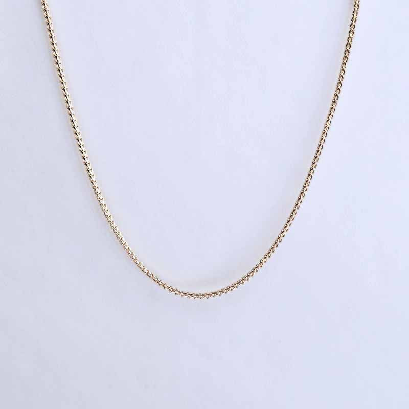 A delicate gold chain necklace draped in a U-shape against a plain white background.
