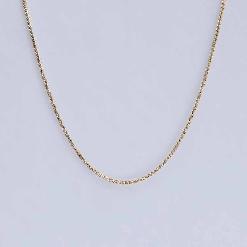 A delicate gold chain necklace draped in a U-shape against a light gray background.