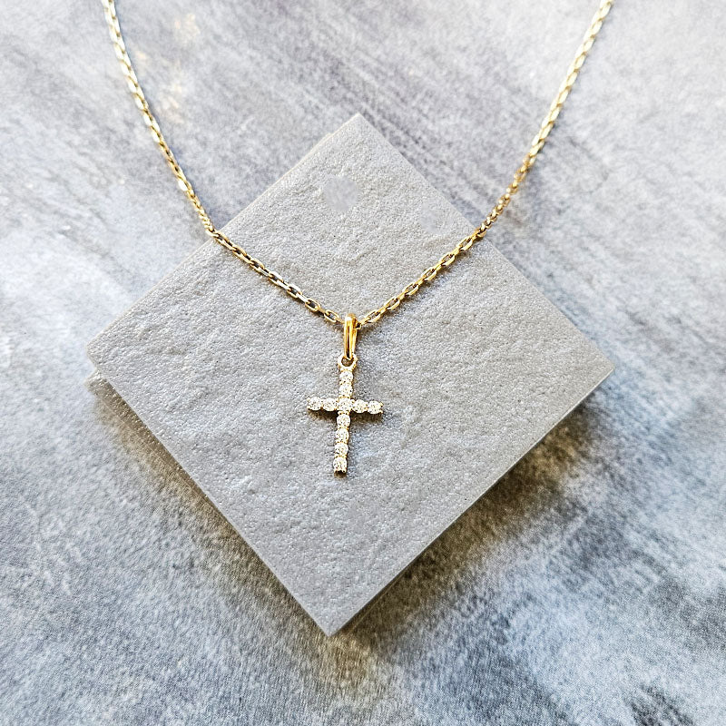 Gold cross necklace on a gray stone surface