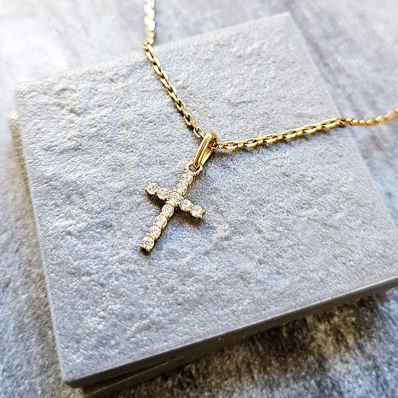 Gold cross necklace on a gray stone surface