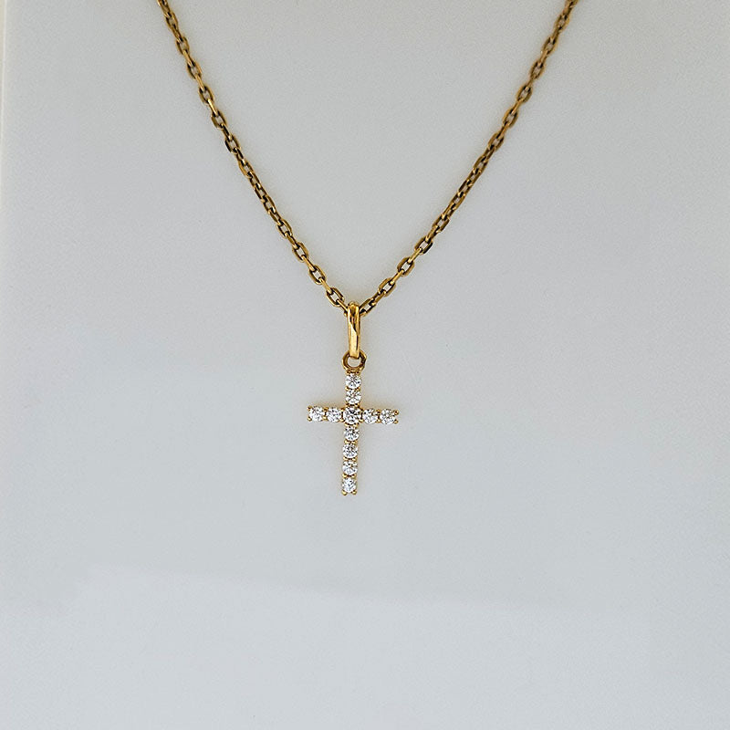 Gold necklace with a diamond cross pendant on a light gray background