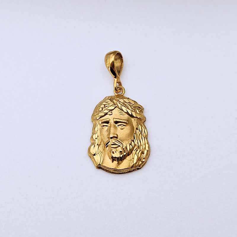 A gold Jesus Christ pendant featuring a detailed relief of His face with a crown of thorns, shown on a plain light background.