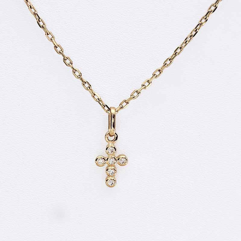 A gold cross pendant necklace with small clear stones, displayed on a delicate gold chain against a white background.