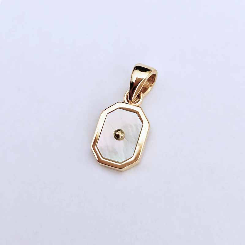 A gold pendant with an octagonal outline and a white mother-of-pearl inlay featuring a small central gold bead, shown on a plain light background.
