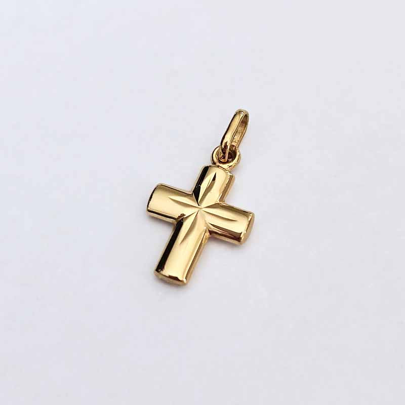 A polished yellow gold cross pendant with a smooth, reflective finish and a small integrated loop at the top, shown on a plain light gray background.