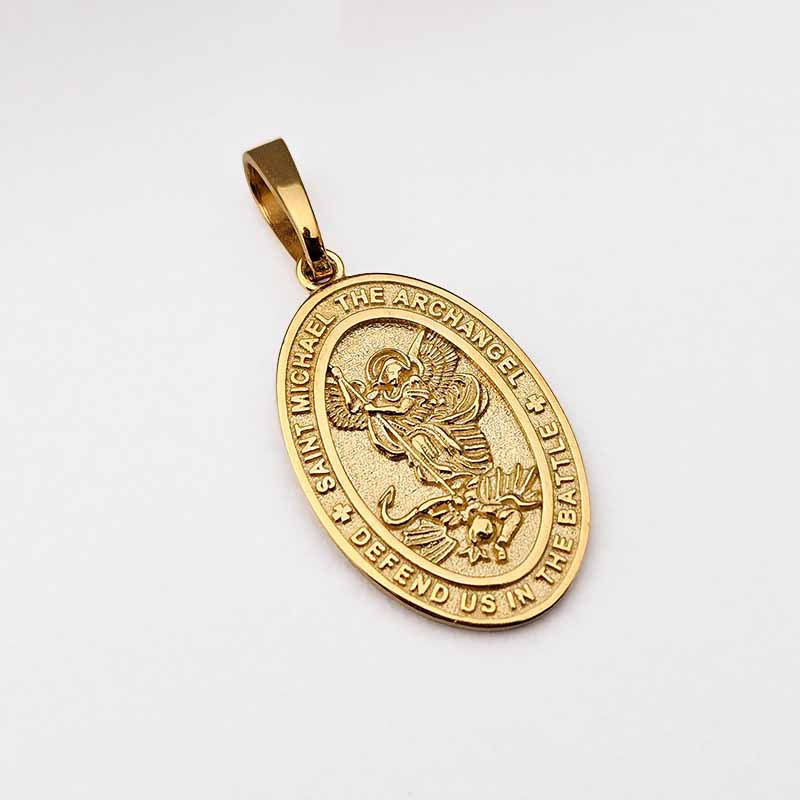 A gold oval Saint Michael the Archangel pendant with a detailed relief of the saint and surrounding text, shown on a plain light background.