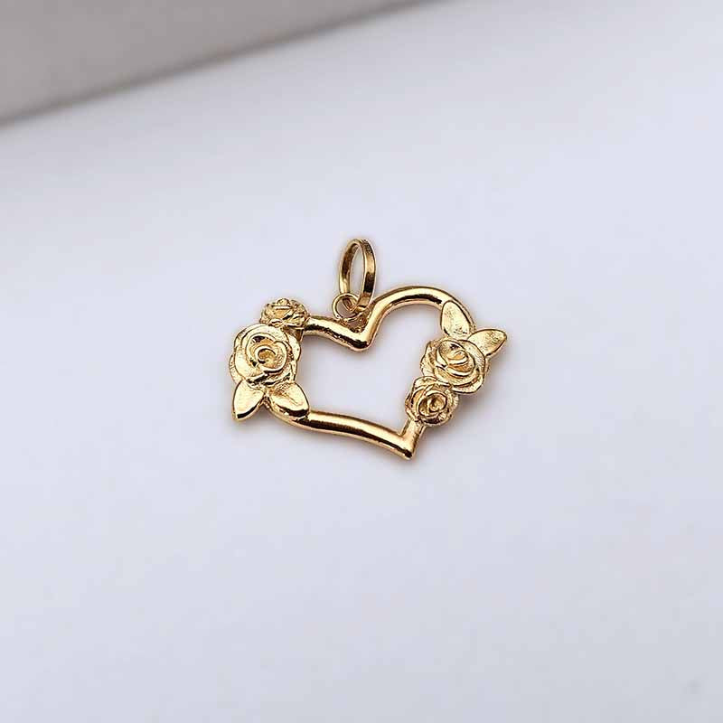 A gold heart-shaped pendant charm with rose details on the left and right sides, resting on a plain white surface.