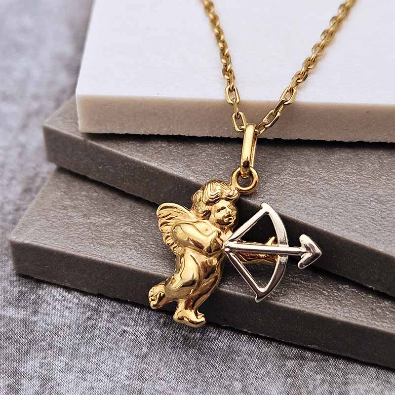 Gold cupid pendant necklace with a bow and arrow, displayed on stacked gray and white blocks.