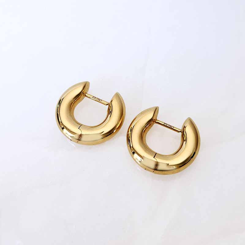 A pair of polished gold round-shaped hoop earrings on a clean, light off-white background.