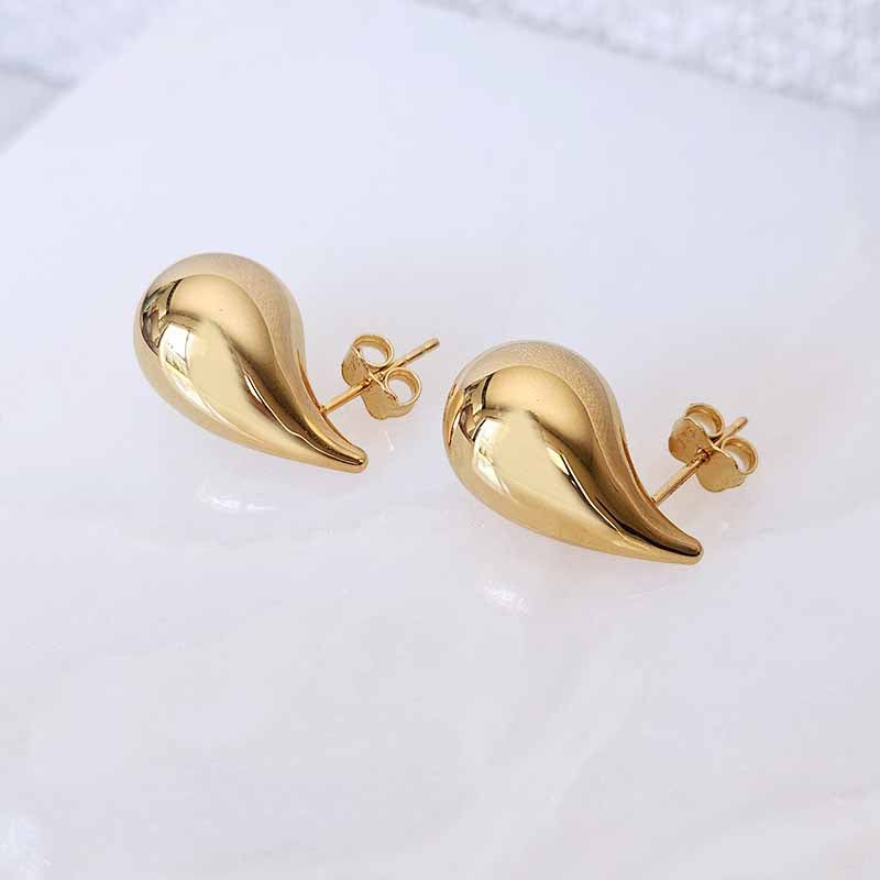 A pair of gold teardrop-shaped stud earrings with a polished finish and butterfly backings, displayed on a clean white surface.