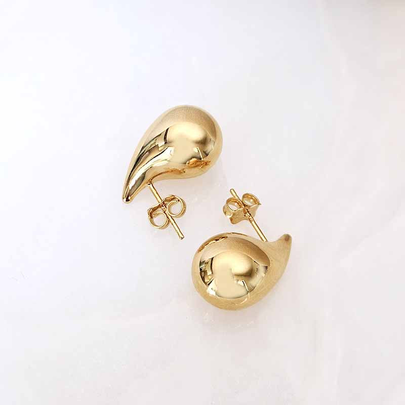 A pair of polished gold teardrop-shaped stud earrings with butterfly backings, displayed on a clean white background.