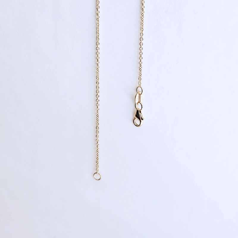 A close-up of a delicate gold chain necklace showing the extender section with a lobster clasp and a small hanging ring, set against a plain white background.