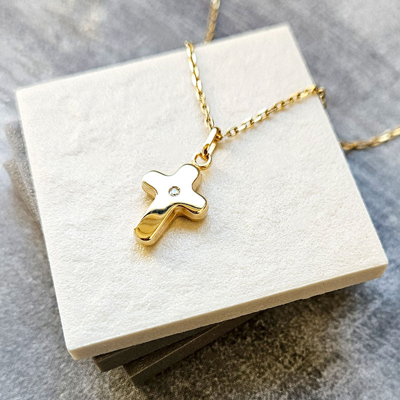 gold cross pendant with a cubic zirconia stone on a gold chain