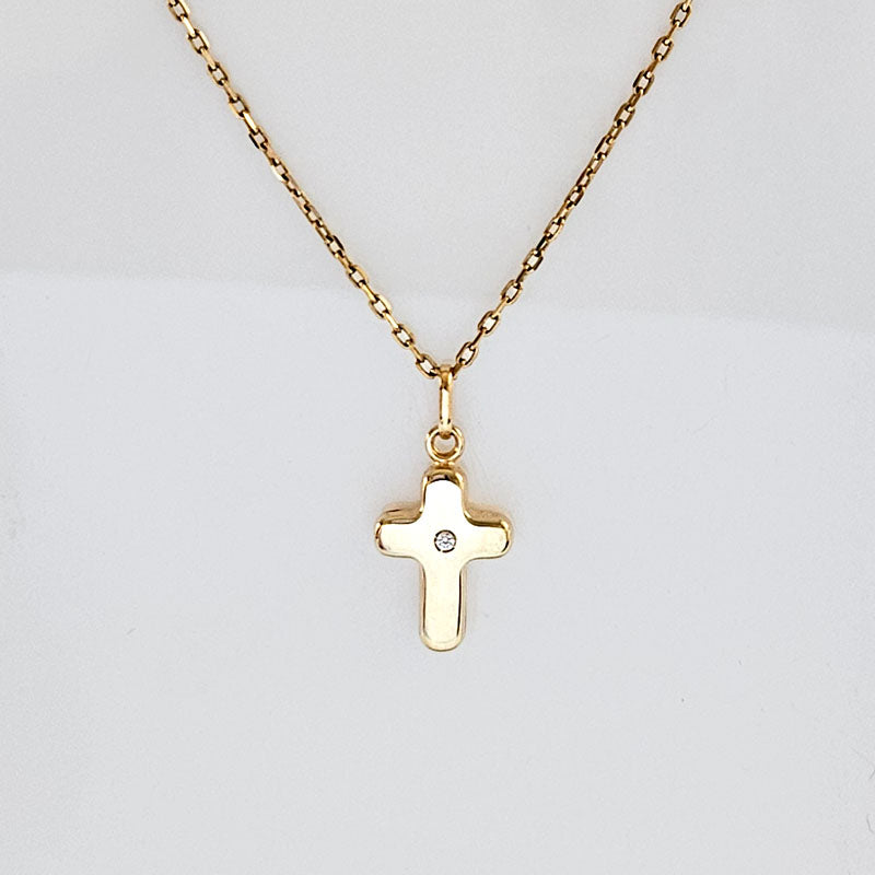 Gold cross necklace with a diamond on a light gray background