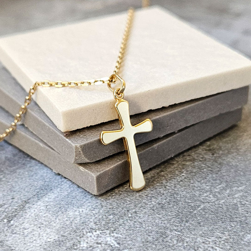 Gold cross necklace on a stone surface