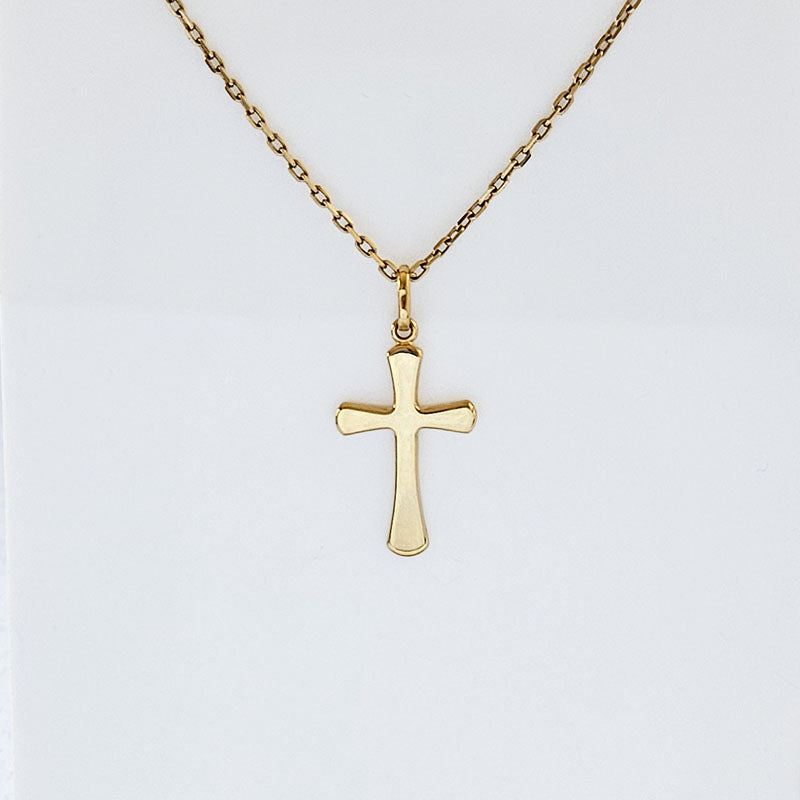Gold cross necklace on a light gray background