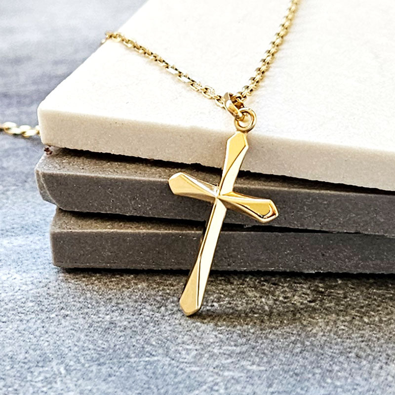 Gold cross necklace on a stone surface