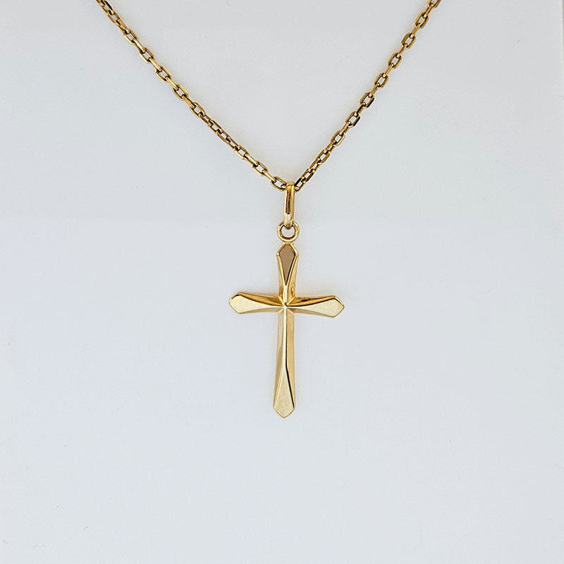 Gold cross pendant on a gold chain against a white background