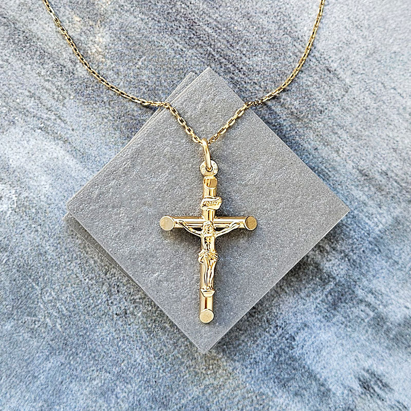 Gold crucifix necklace on a gray stone surface