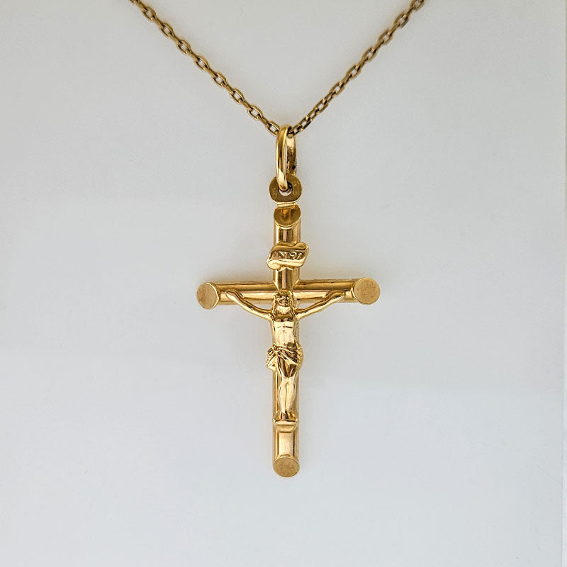 Gold crucifix pendant on a chain against a white background