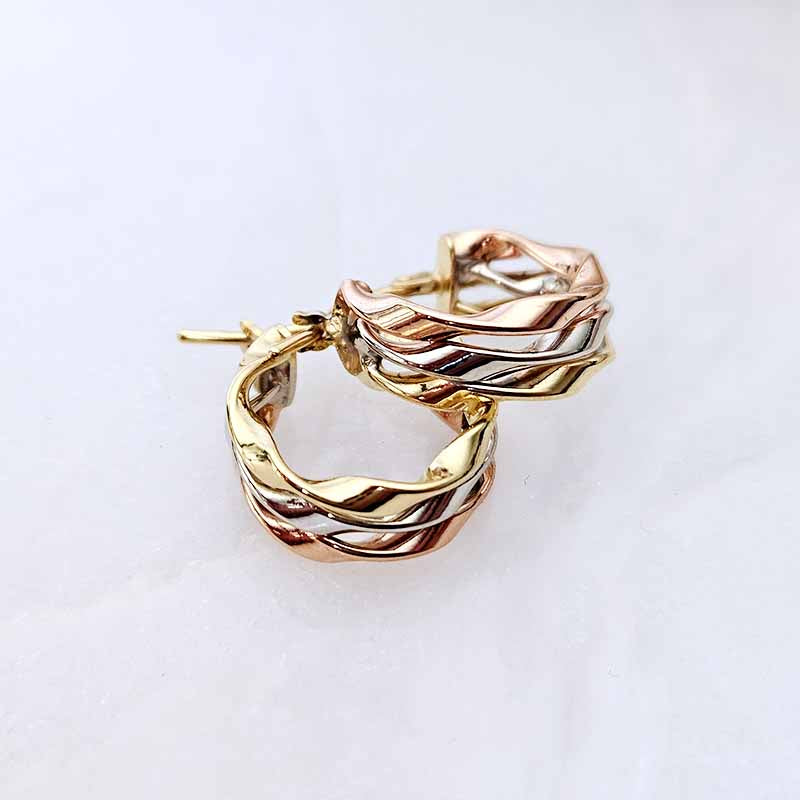 A pair of twisted hoop earrings in a three-tone yellow gold, white gold and rose gold finish, displayed on a clean white background.