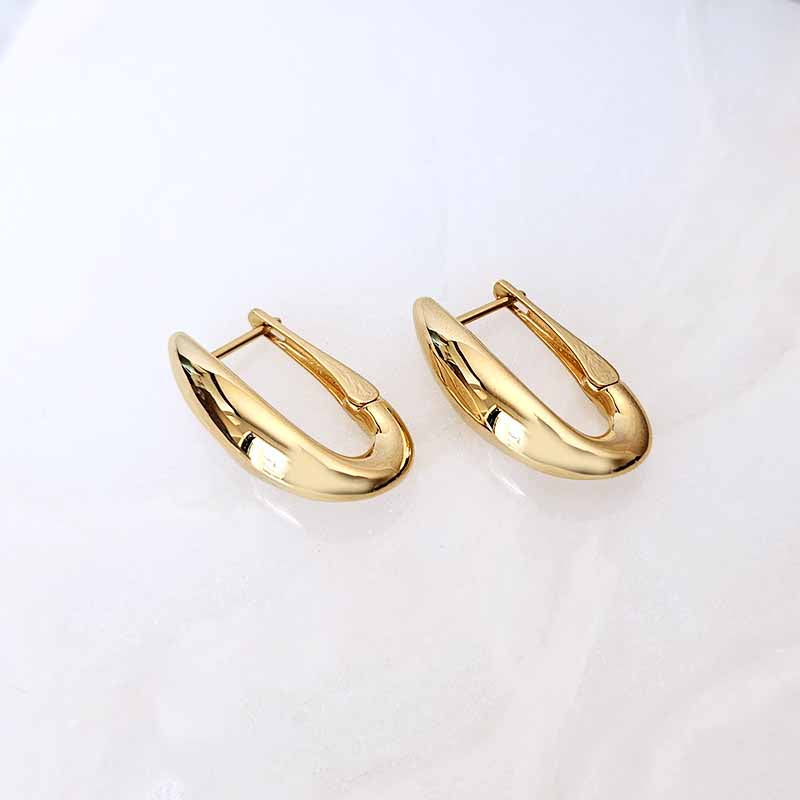 A pair of polished gold huggie hoop earrings on a clean, light off-white background.