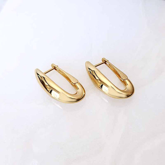 A pair of polished gold huggie hoop earrings on a clean, light off-white background.