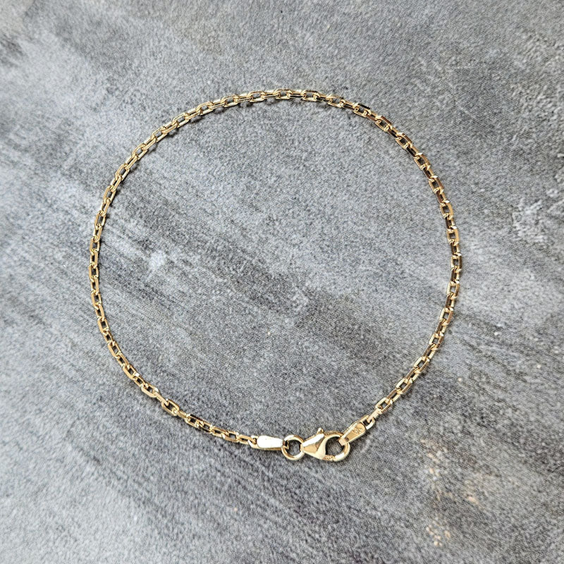 Gold chain bracelet on a gray stone surface
