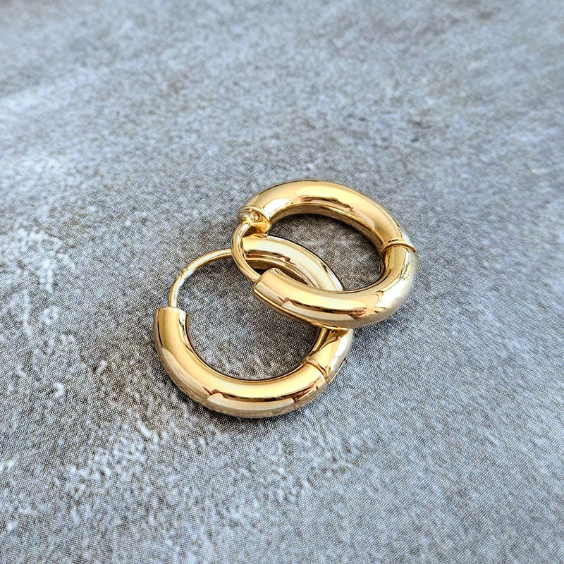 Gold hoop earrings on a textured gray surface