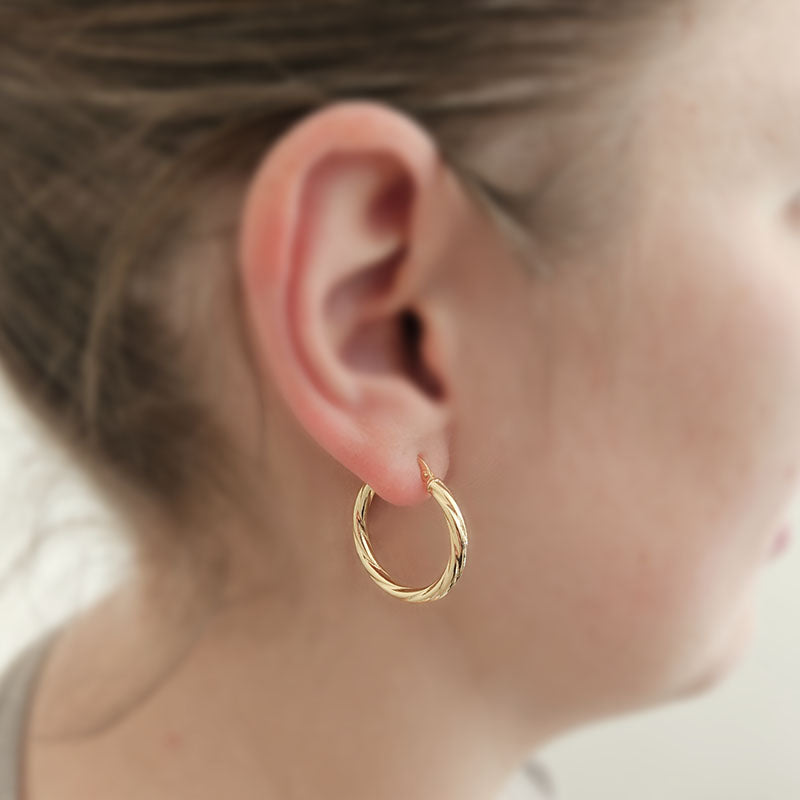 Gold hoop earring worn by a person with a blurred background