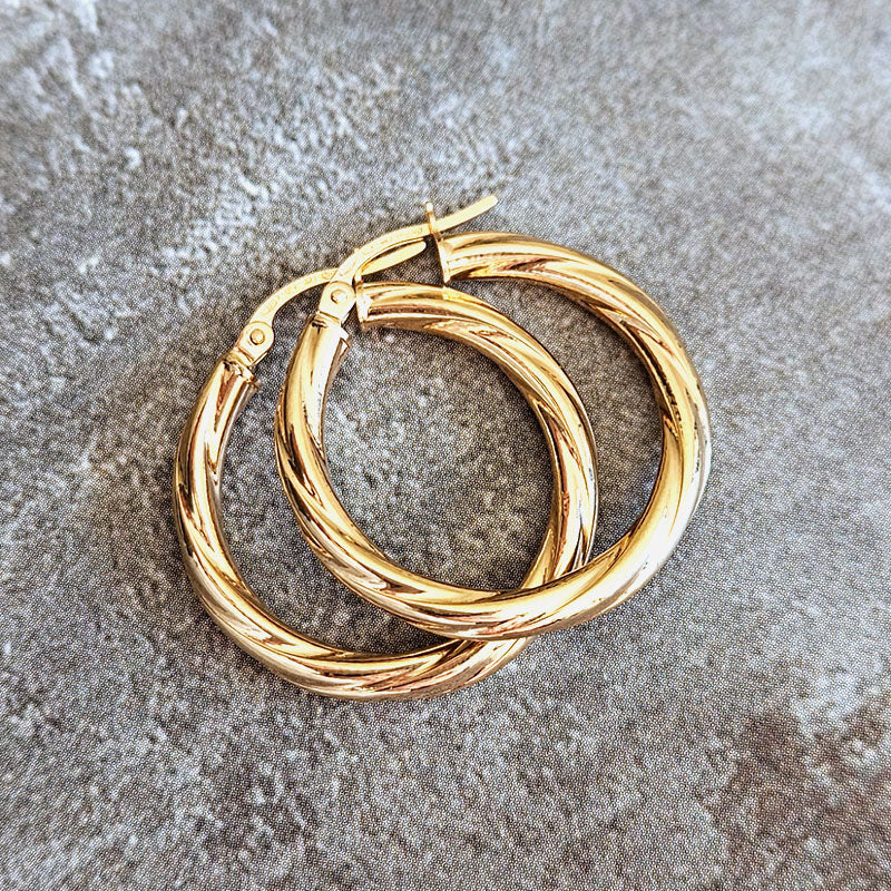 Gold hoop earrings on a textured gray surface