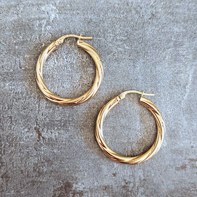 Gold hoop earrings on a textured gray surface